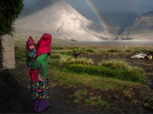 Woman and child in a mountain landscape with a rainbow